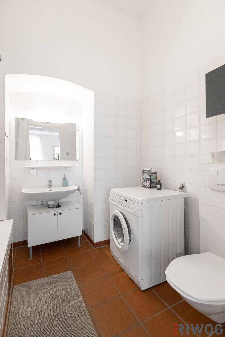 Funktionales Badezimmer mit WC, Waschbecken und praktischer Waschmaschine.