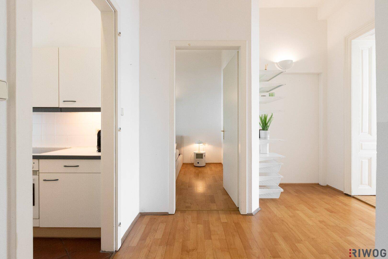 Heller Flur mit Parkettboden und offenen Durchgängen zu Küche und Schlafzimmer.