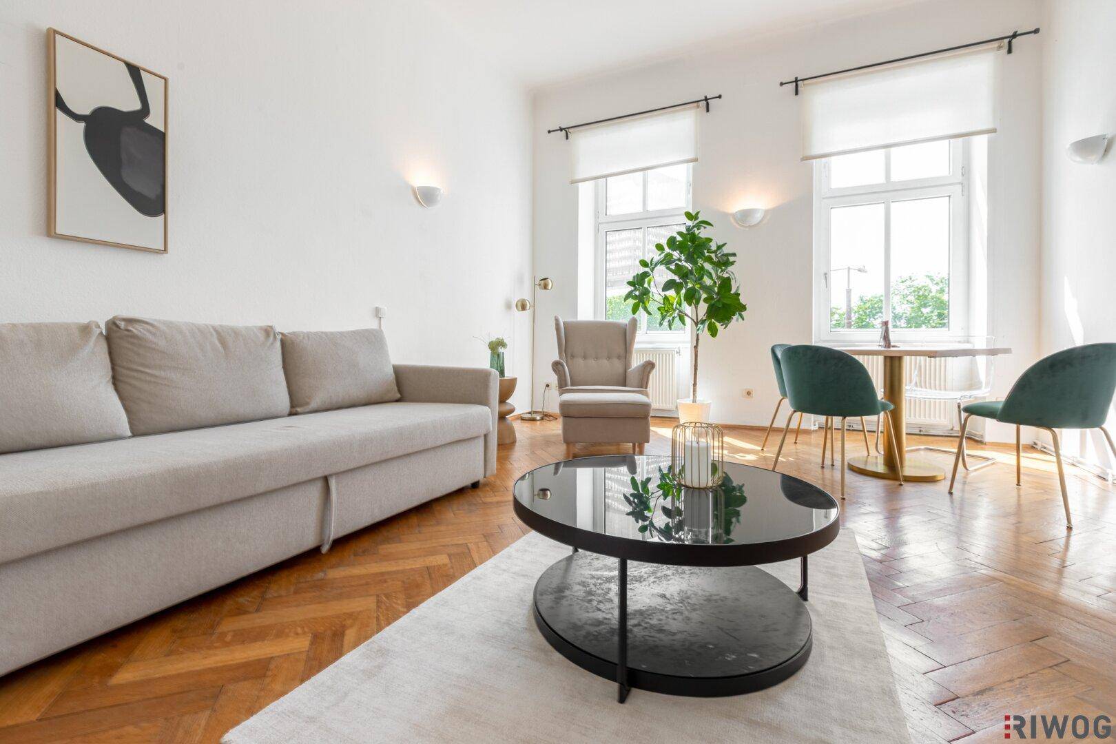 Geräumiger Wohnbereich mit beigem Sofa, modernem Couchtisch und hellem Fischgrätparkett.