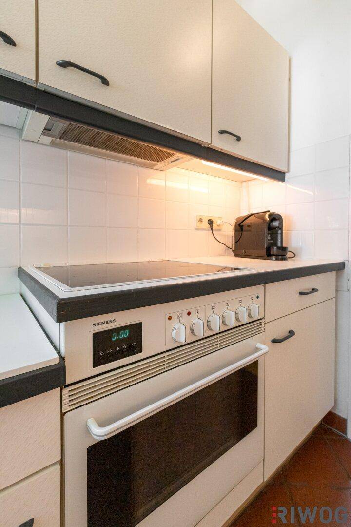 Küche mit Elektrokochfeld, Backofen von Siemens und praktischen Oberschränken.