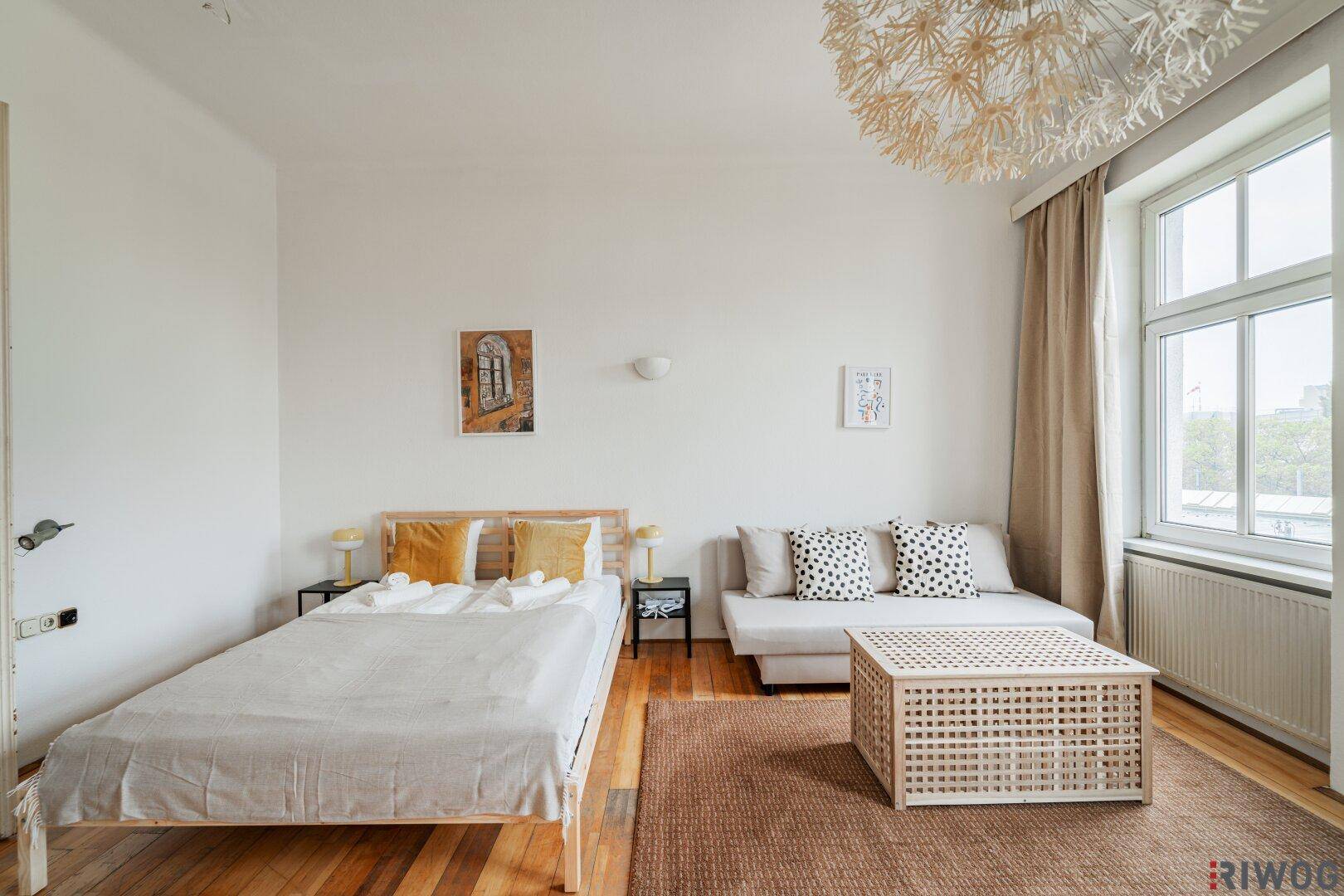 Geräumiges Zimmer mit Holzboden, bequemer Schlafcouch und dekorativer Hängelampe.