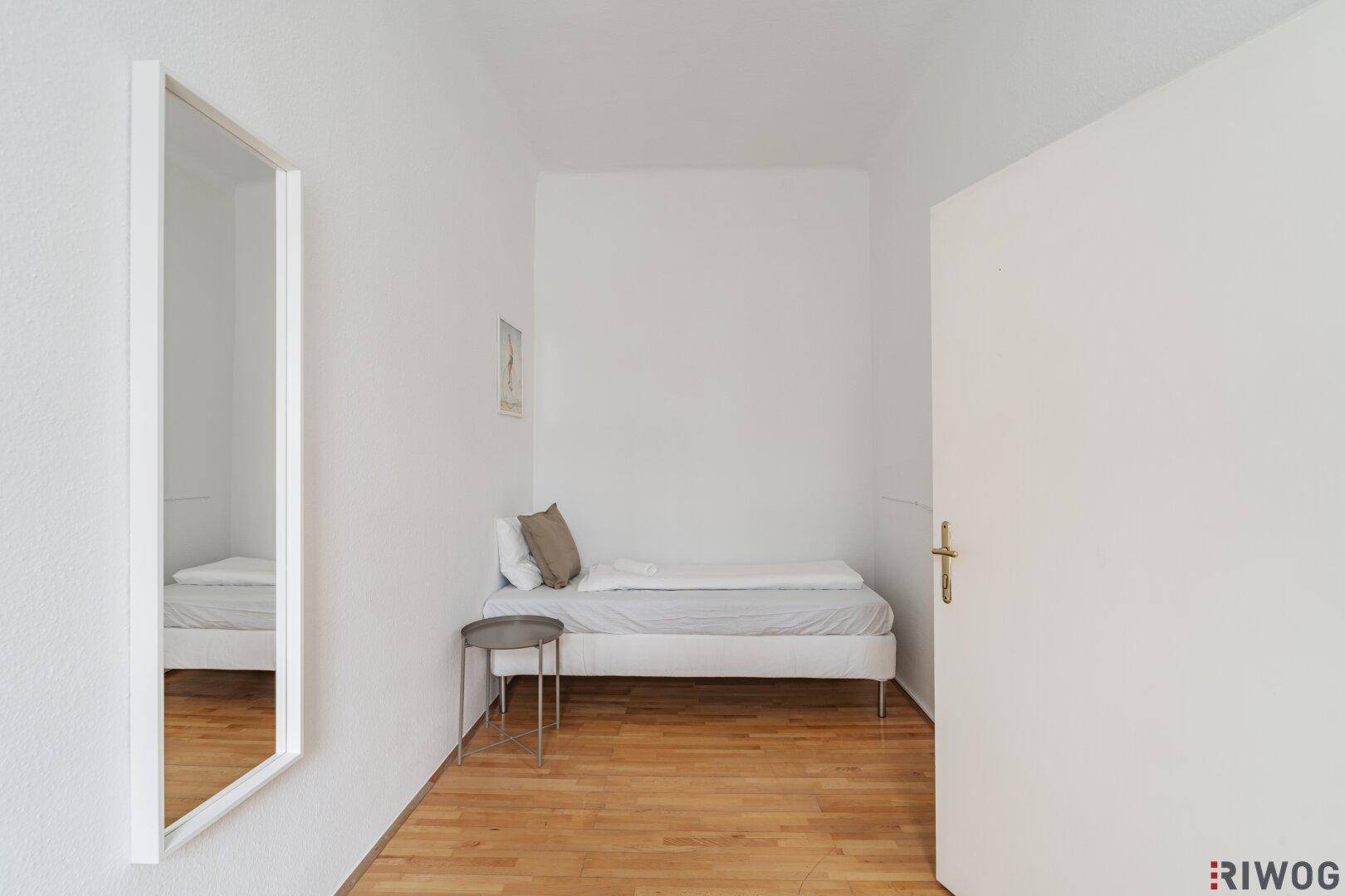 Gemütliches Schlafzimmer mit Holzboden und Spiegel, bietet eine ruhige Rückzugsmöglichkeit.