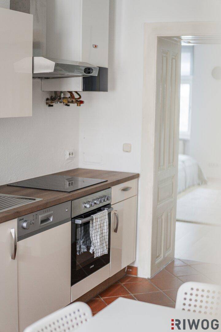 Detailansicht der Küche mit modernem Induktionskochfeld, Backofen und integriertem Geschirrspüler.