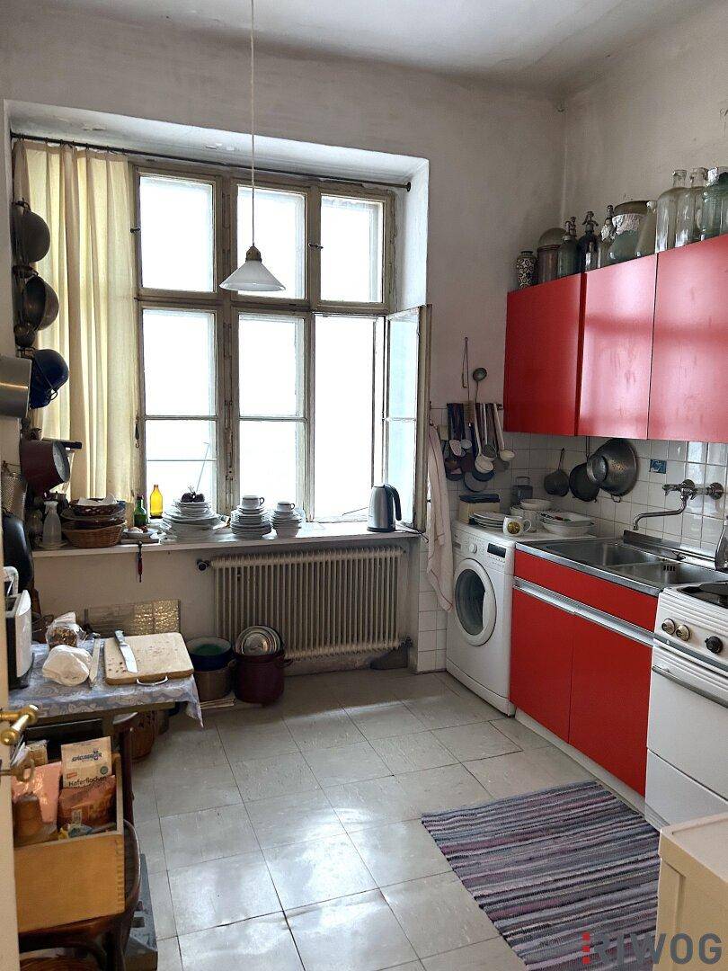 Küche mit roten Schränken, Fliesenboden und Waschmaschine.