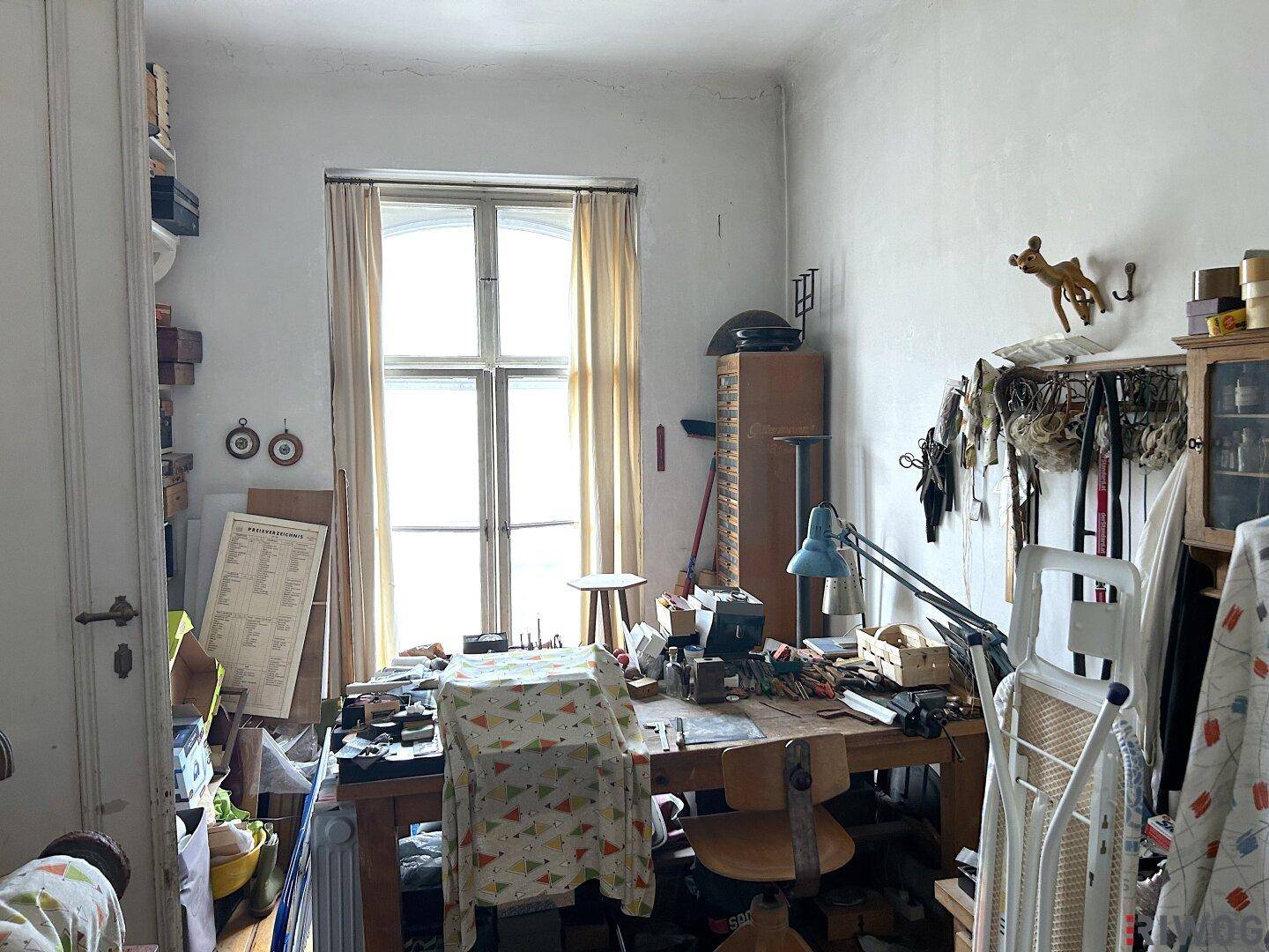 Arbeitszimmer mit großem Fenster, viel Tageslicht und Renovierungsbedarf.