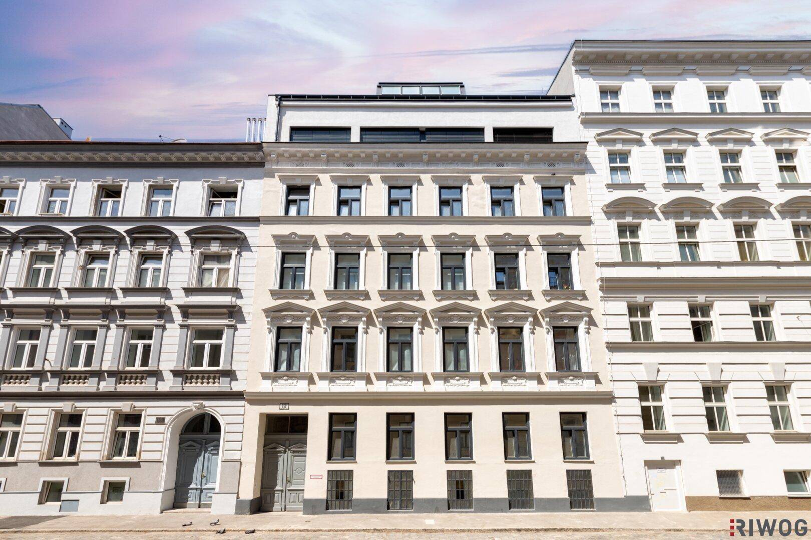 Historische Fassade eines Mehrfamilienhauses mit modernem Dachausbau in städtischer Umgebung.