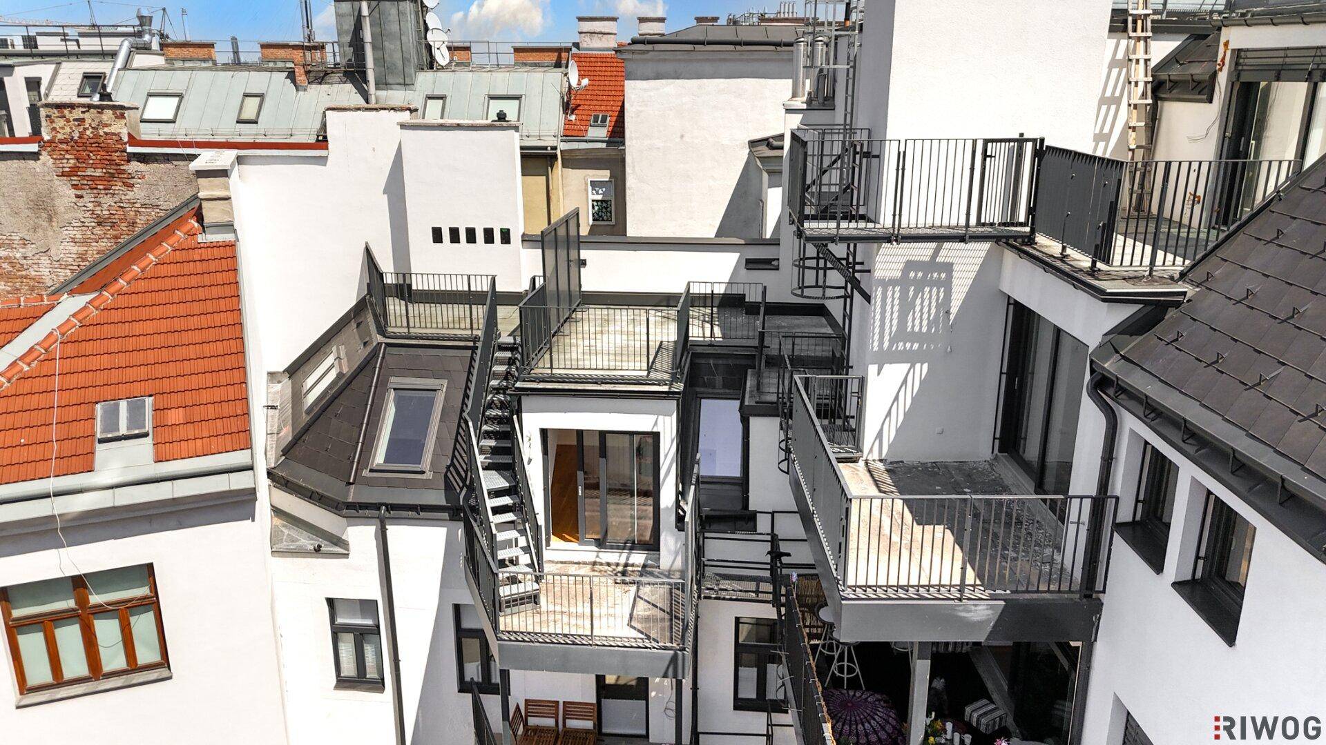 Vogelperspektive auf das moderne Gebäudeensemble mit verschiedenen Dachterrassen und Balkonen.