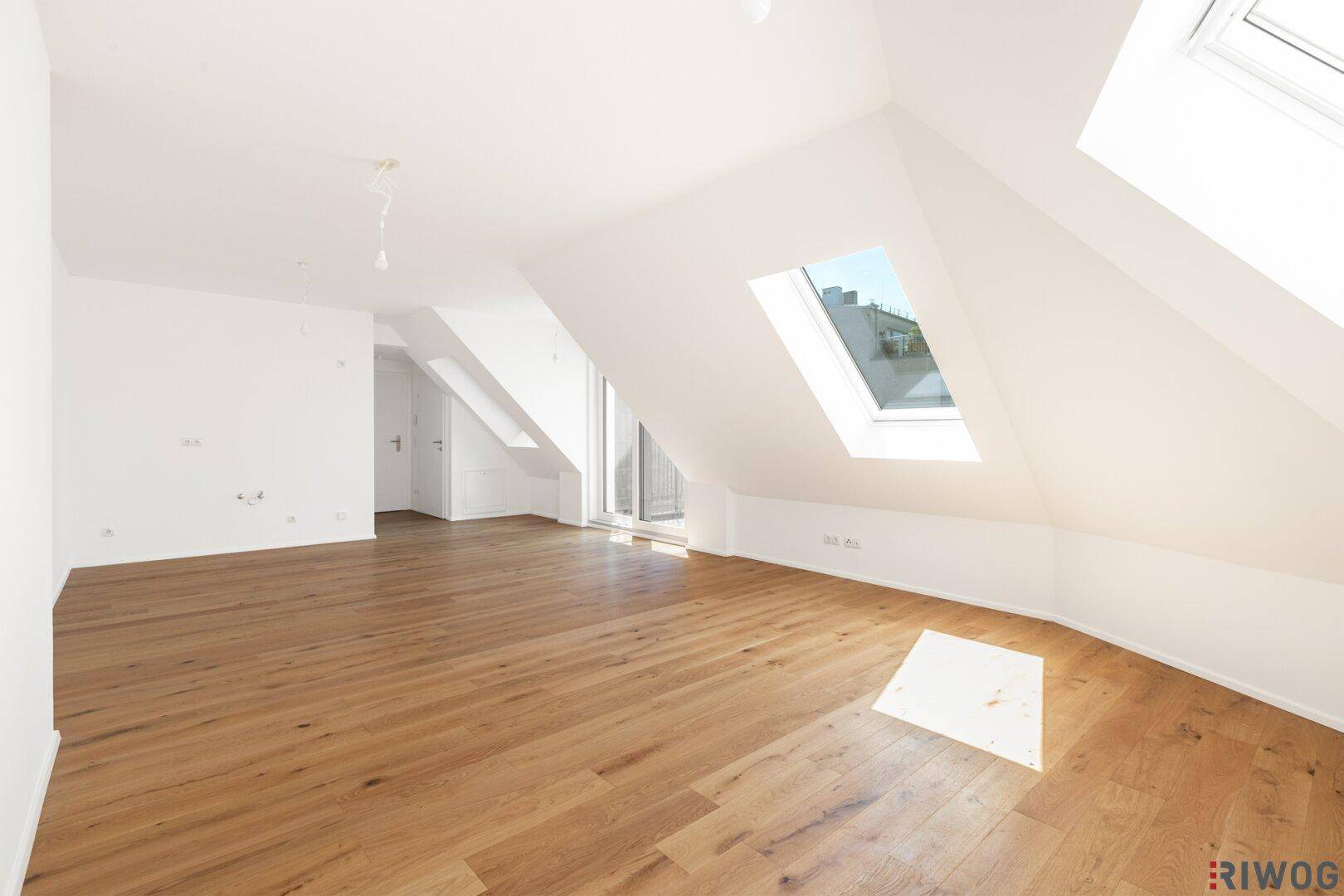 Heller Dachgeschossraum mit Holzboden, Dachfenstern und viel natürlichem Licht.