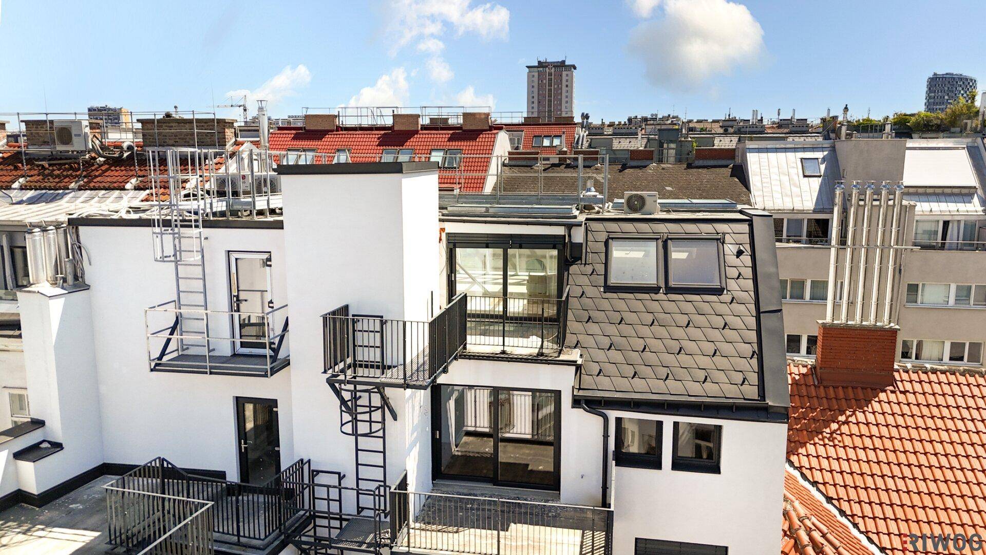 Überblick über die Dachlandschaft der Stadt mit verschiedenen Balkonen und Terrassenbereichen.