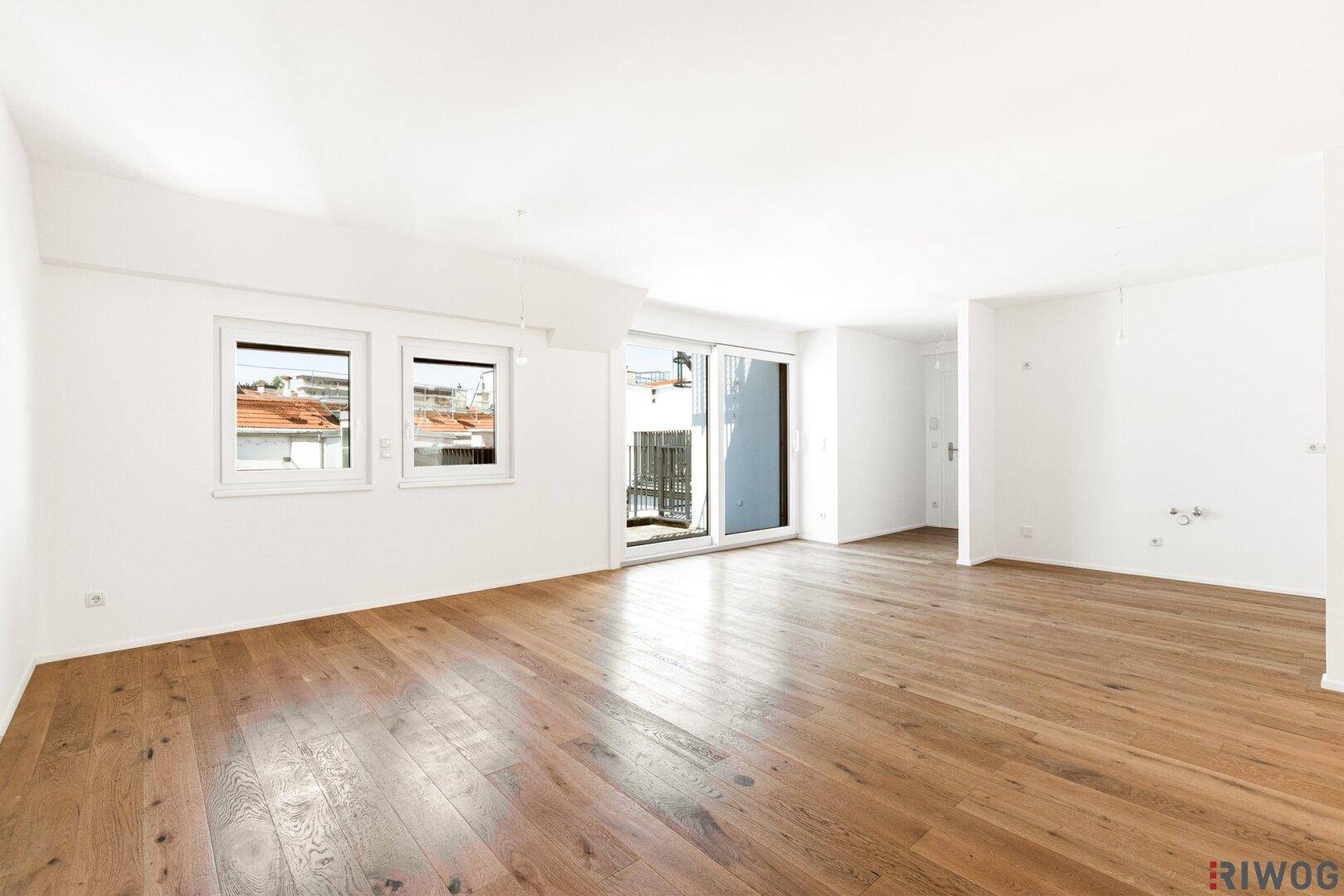 Geräumiger, heller Wohnbereich mit hochwertigem Parkettboden und Zugang zum Balkon.