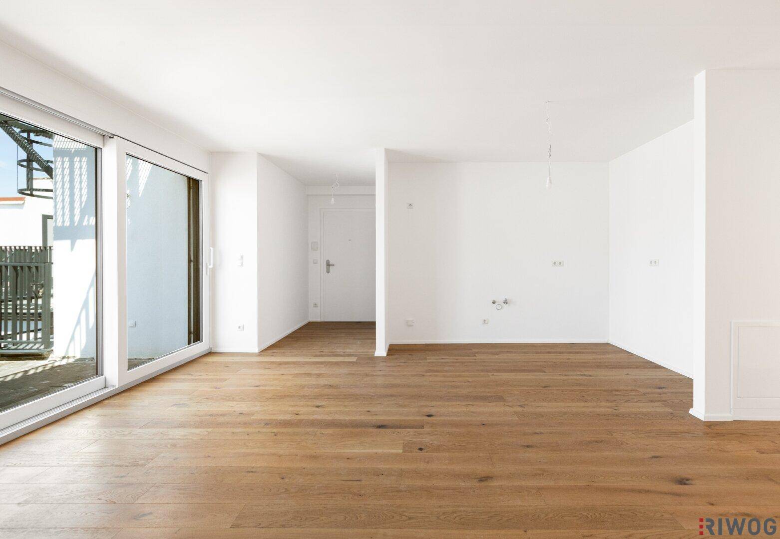 Offener Wohnbereich mit hellem Parkettboden und viel Tageslicht, bereit für individuelle Gestaltung.