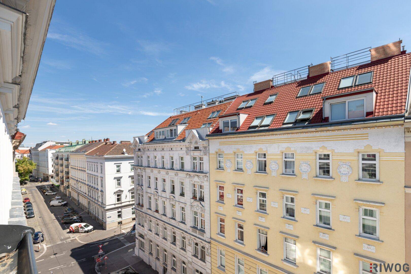 Panoramablick über eine städtische Straße mit charmanten Altbauten und vielen Dachfenstern.