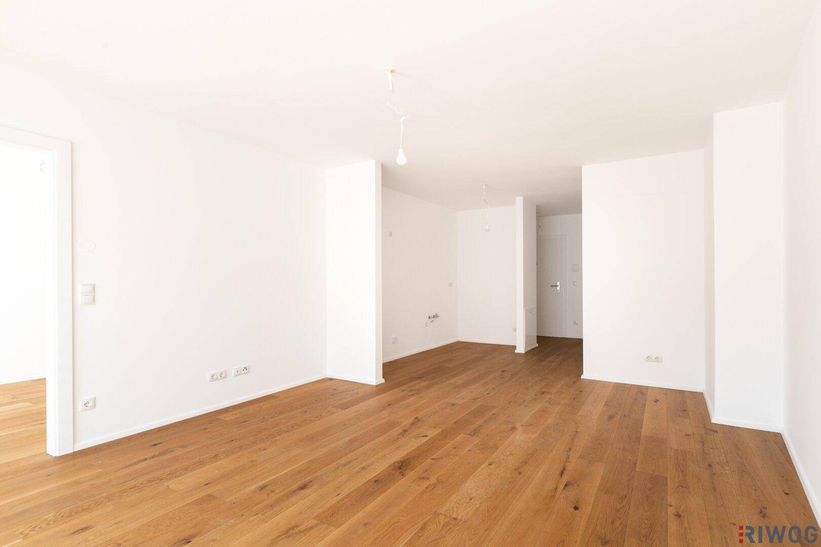 Heller Flur mit weiß gestrichenen Wänden und hochwertigem Holzboden, der zu weiteren Räumen führt.