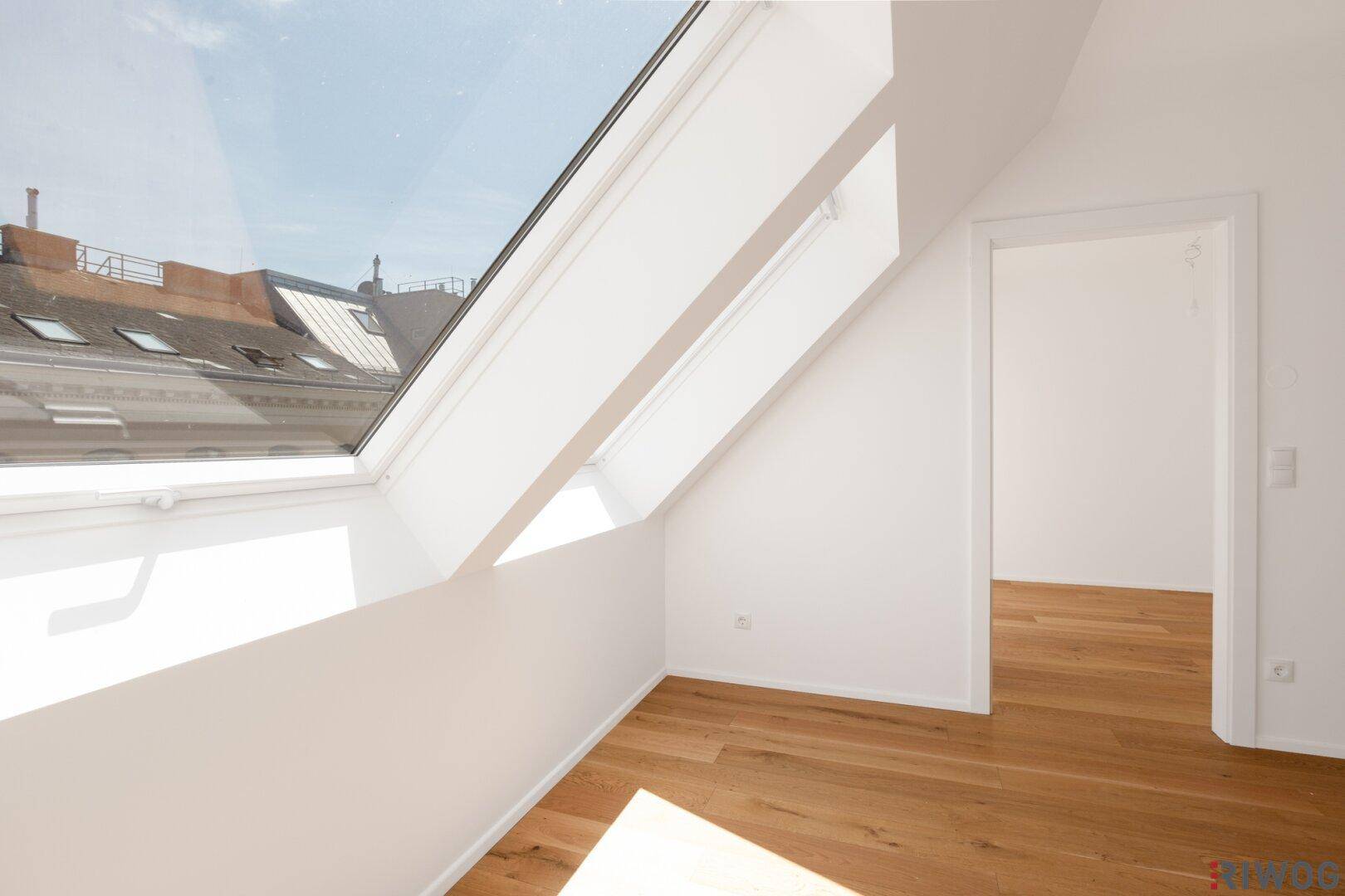 Großes Dachfenster bietet einen Blick auf die umliegenden Dächer und lässt viel Licht in den Raum.