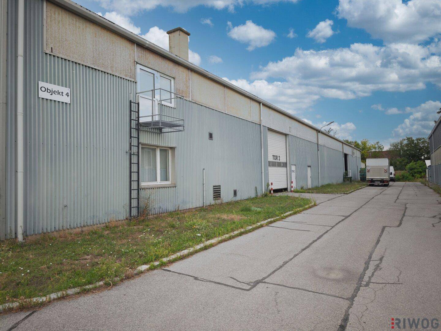 Industrielles Gebäude mit Wellblechfassade, Laderampe und einer kleinen externen Plattform.