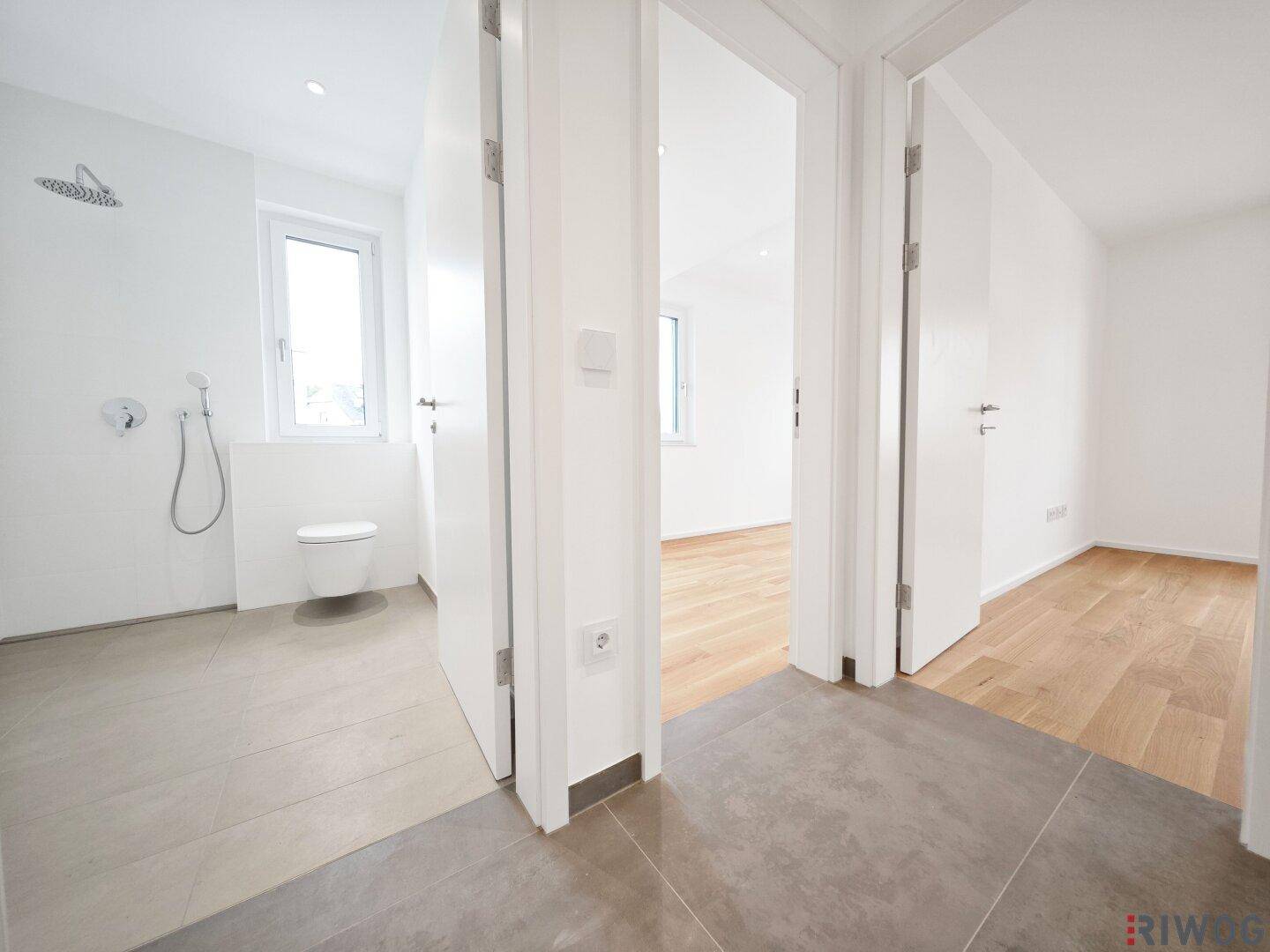 Modernes Badezimmer mit ebenerdiger Dusche, WC und Fenster für Tageslicht.