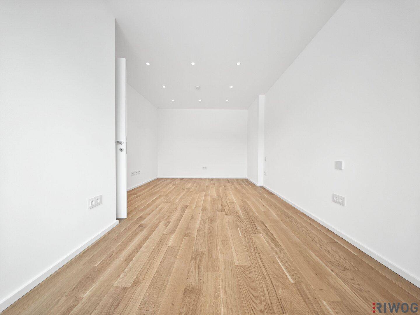 Leeres Zimmer mit Parkettboden und weißen Wänden, bereit zur individuellen Gestaltung.