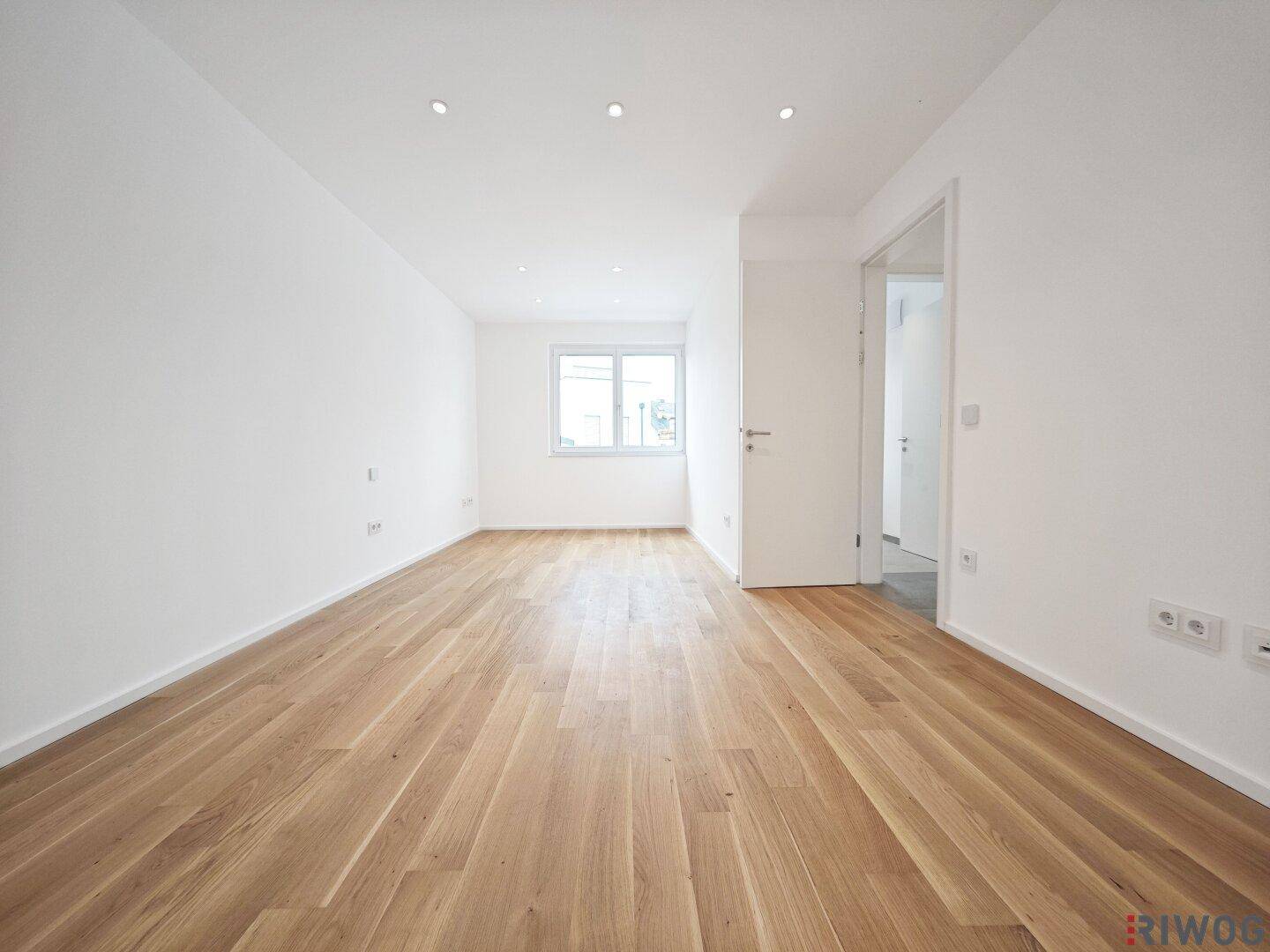 Geräumiges, helles Zimmer mit Parkettboden und großem Fenster.