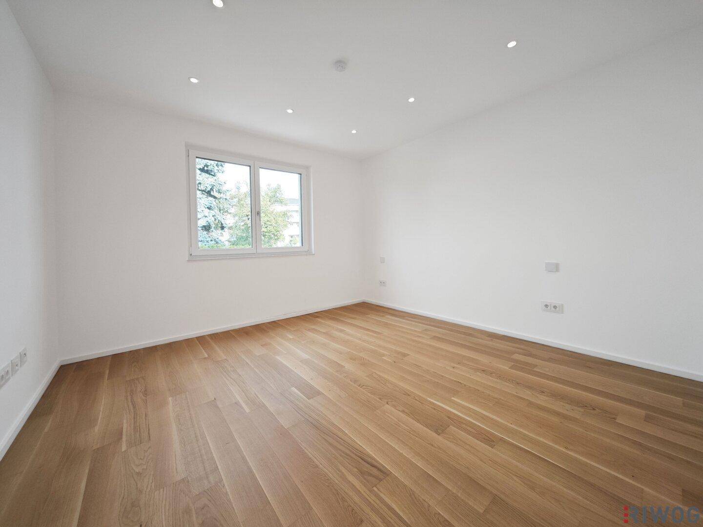Geräumiges Zimmer mit Parkettboden und großem Fenster, vielseitig nutzbar.