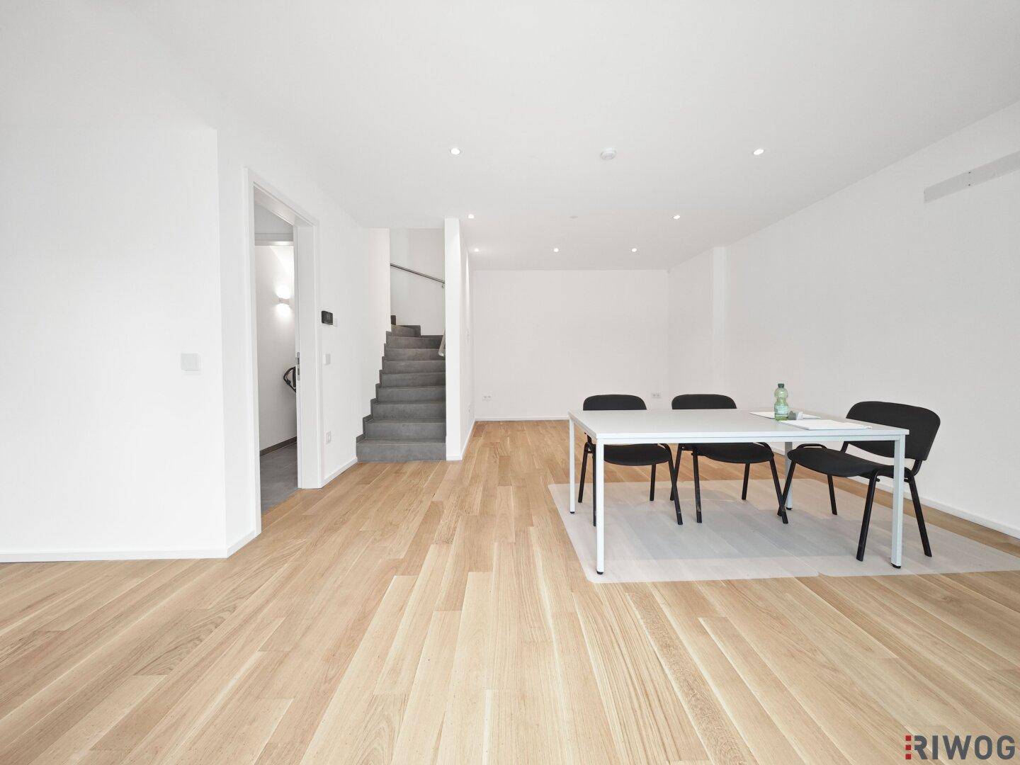 Geräumiger Wohn- und Essbereich mit Parkettboden und offener Treppe zum Obergeschoss.