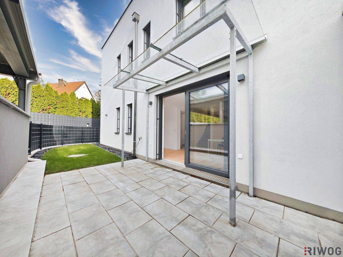 Unmöblierte Terrasse mit Steinplatten und direktem Zugang zum Haus und Garten.