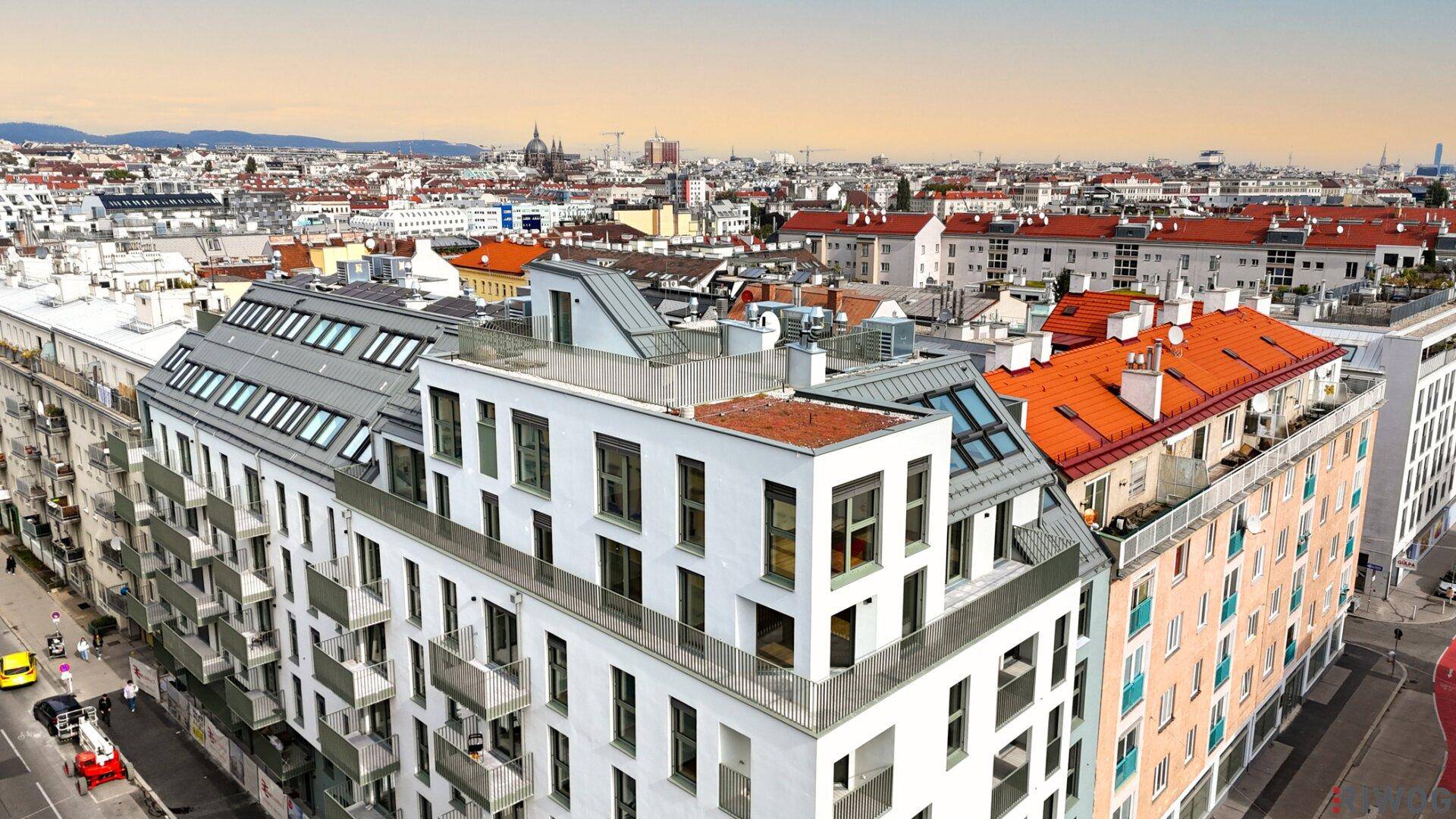 Panoramablick auf ein modernes Wohngebäude in der Stadt mit umliegenden Dächern und Himmel.