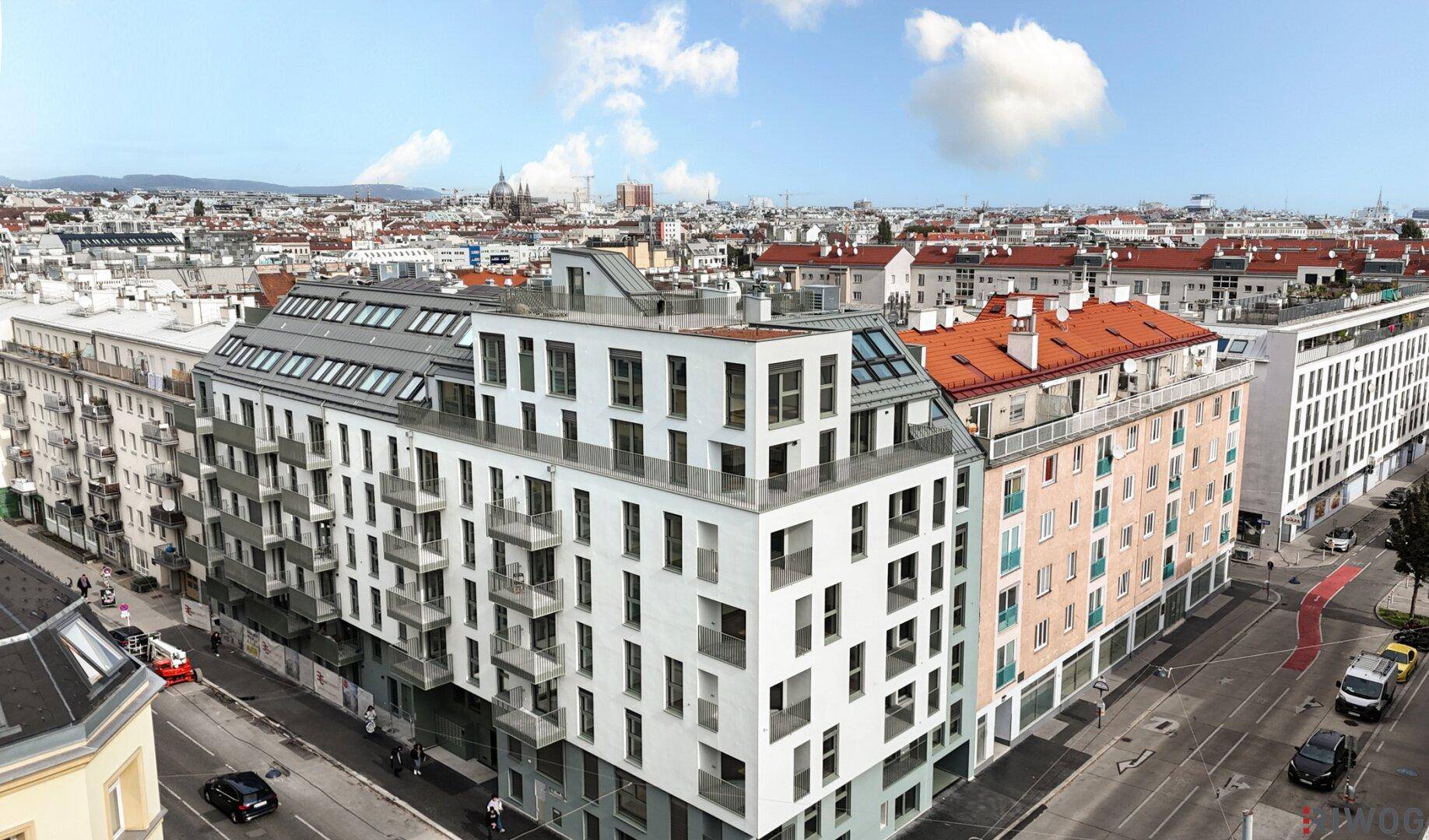 Weitläufige Ansicht eines modernen Wohngebäudes mit Balkonen und der umliegenden Stadtlandschaft.
