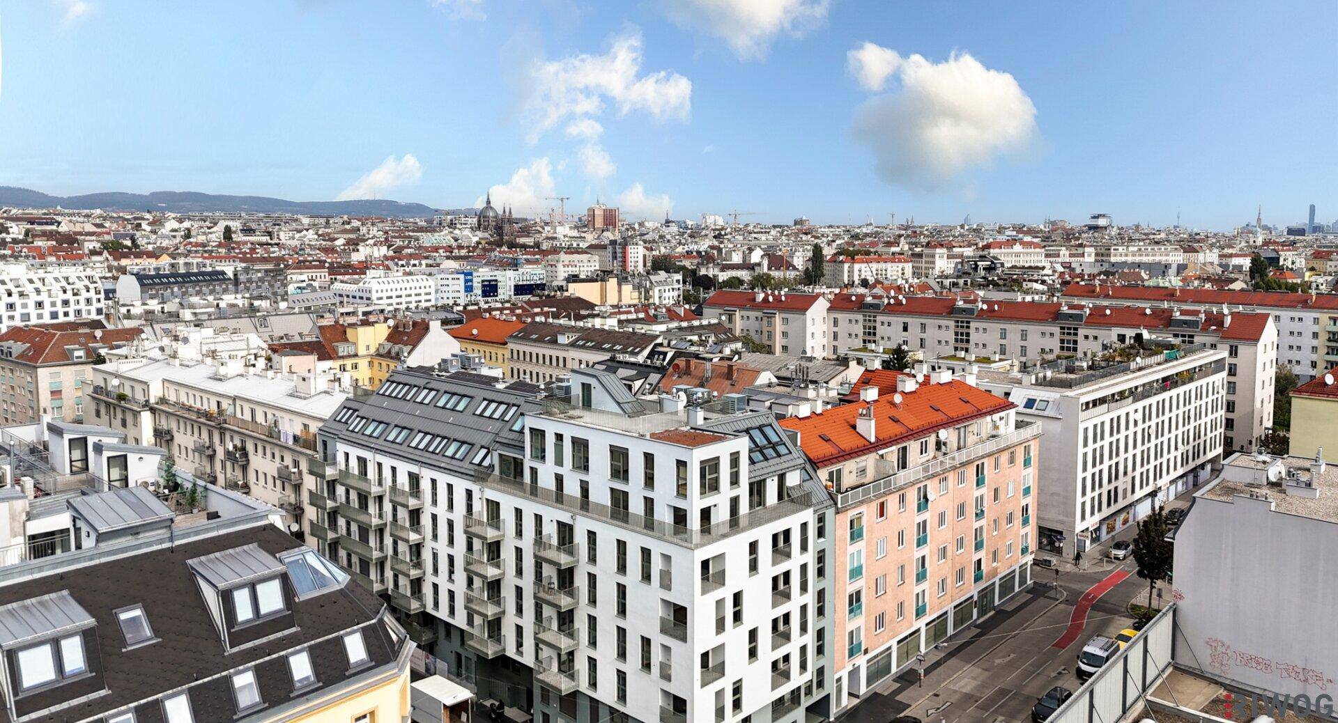 Panoramablick auf einen modernen Wohnkomplex mit vielen Balkonen und der städtischen Umgebung.