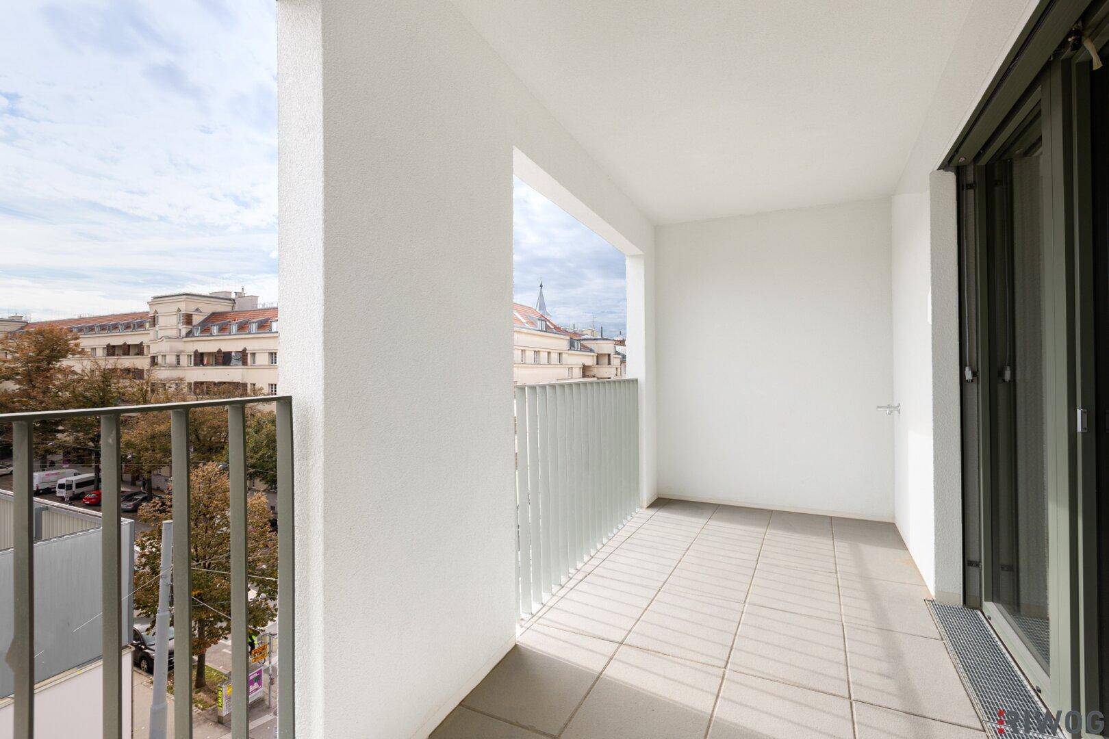 Heller Balkon mit Fliesenboden und Blick auf die Stadt, ideal zum Entspannen.