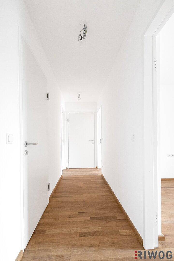 Heller Flur mit Holzboden und weißen Türen, der zu verschiedenen Räumen führt.