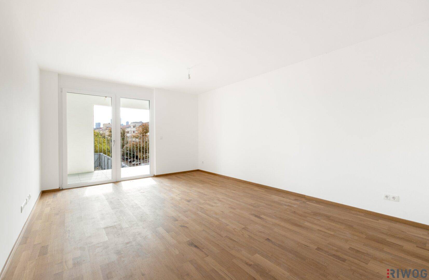 Helles, leeres Zimmer mit Parkettboden und Zugang zum Balkon, bereit zur individuellen Gestaltung.