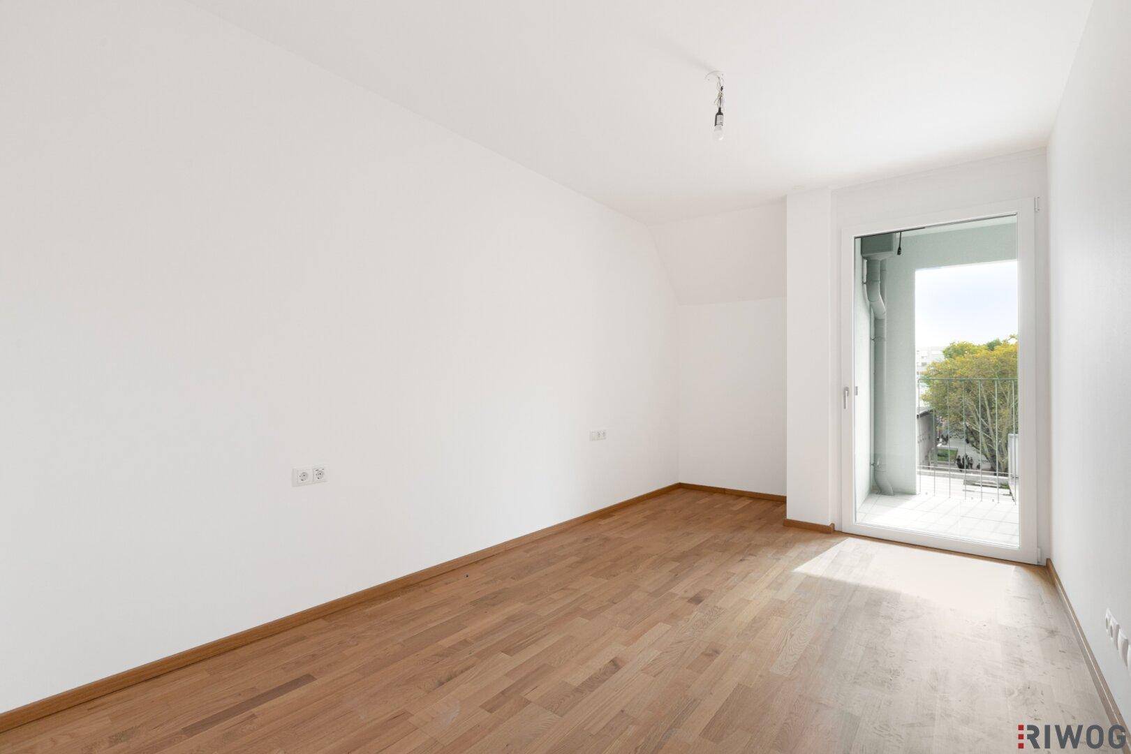 Geräumiges Schlafzimmer mit Parkettboden und direktem Zugang zum Balkon, bietet Komfort und Licht.