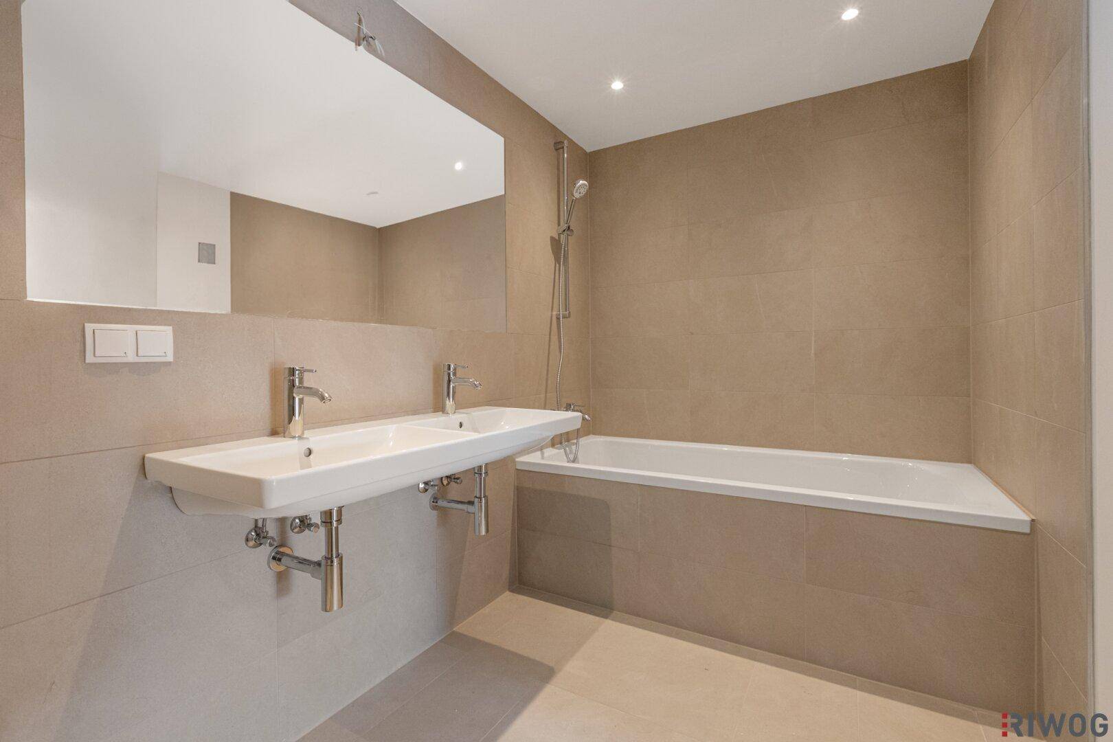 Helles Badezimmer mit Doppelwaschbecken und integrierter Badewanne, bietet Komfort und modernes Design.