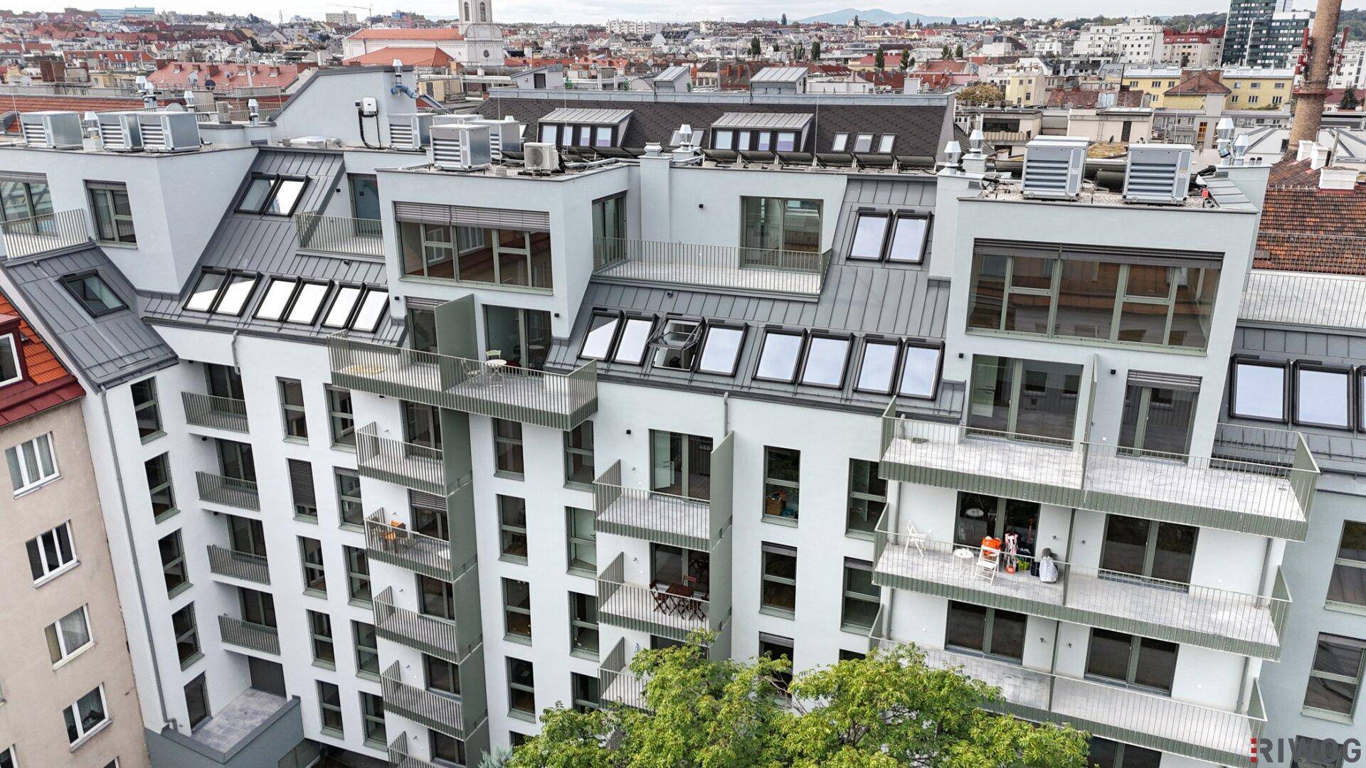 Moderne Wohnanlage mit mehreren Etagen, Balkonen und Dachterrassen in städtischer Umgebung.