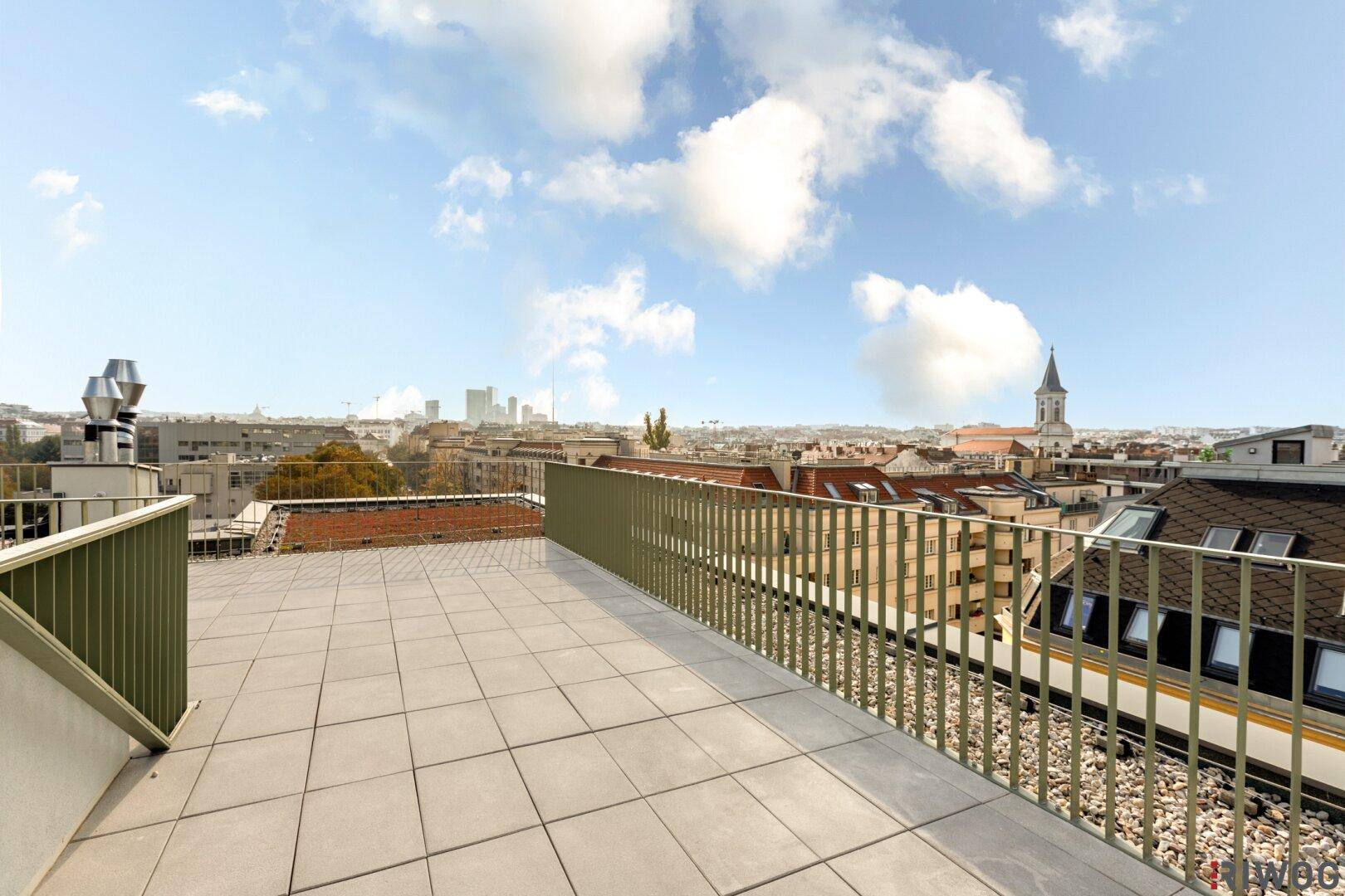 Sonniger Dachterrassenbereich mit Stadtblick und dekorativen Pflanzen.
