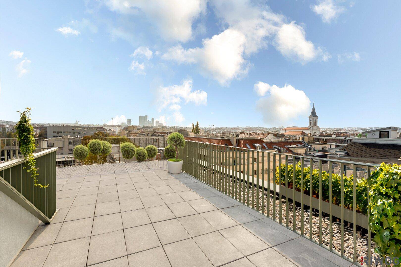 Dachterrasse mit Stadtblick, Fliesenboden und grünen Pflanzen als Dekoration.