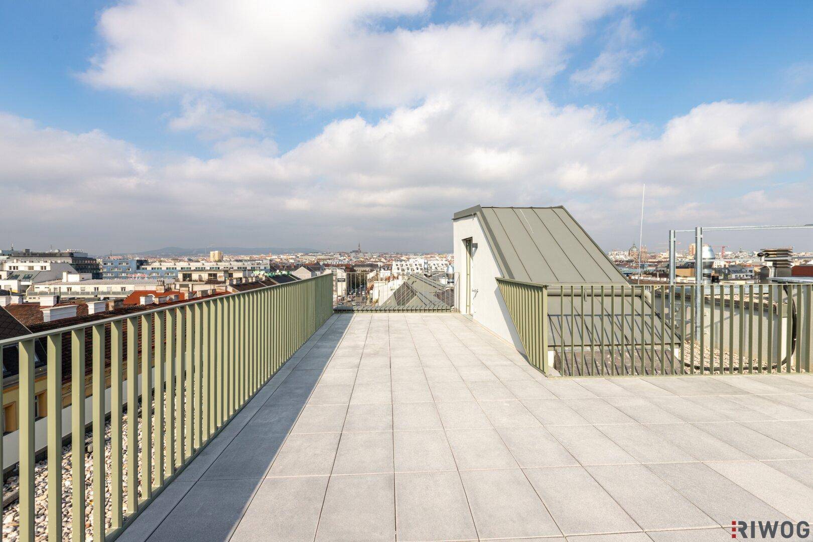 Große Dachterrasse mit Fliesenboden und weitem Blick über die städtische Umgebung.