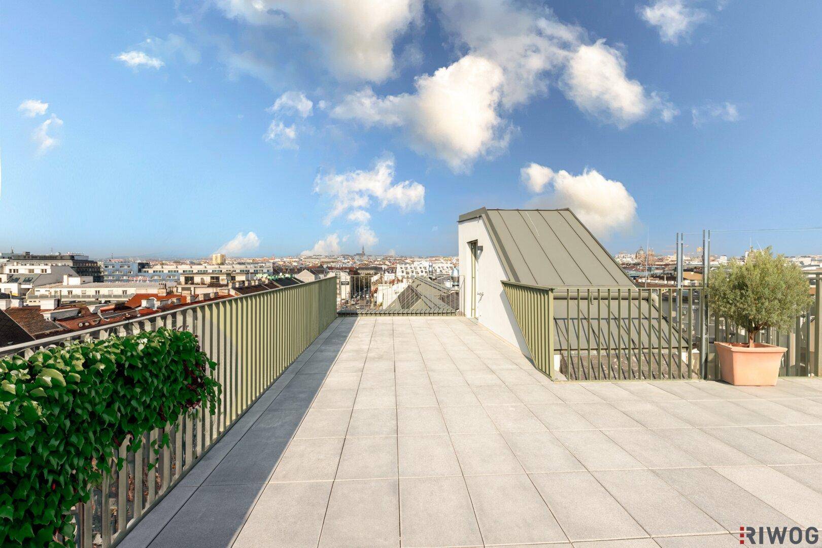 Weitläufige Dachterrasse mit Fliesenboden und Panoramablick über die Stadt.