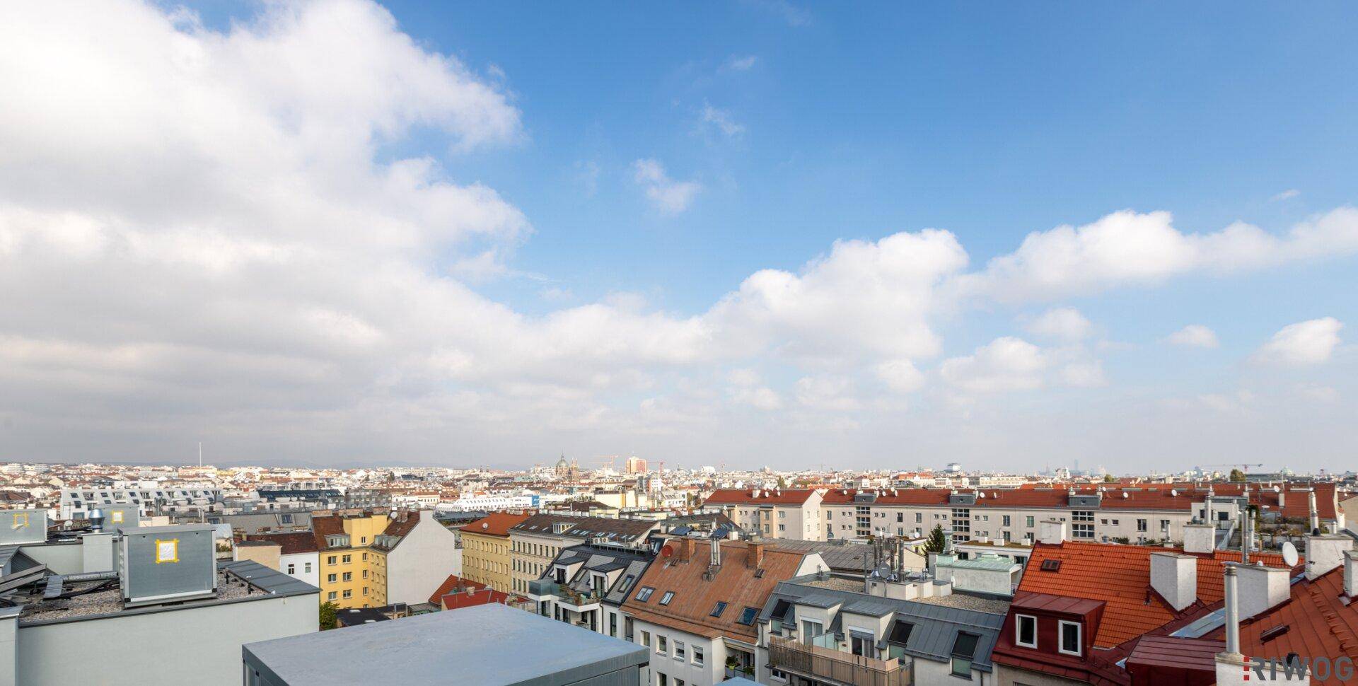 Panoramablick über die Dächer der Stadt mit verschiedenen Gebäudetypen und einem weiten Himmel.