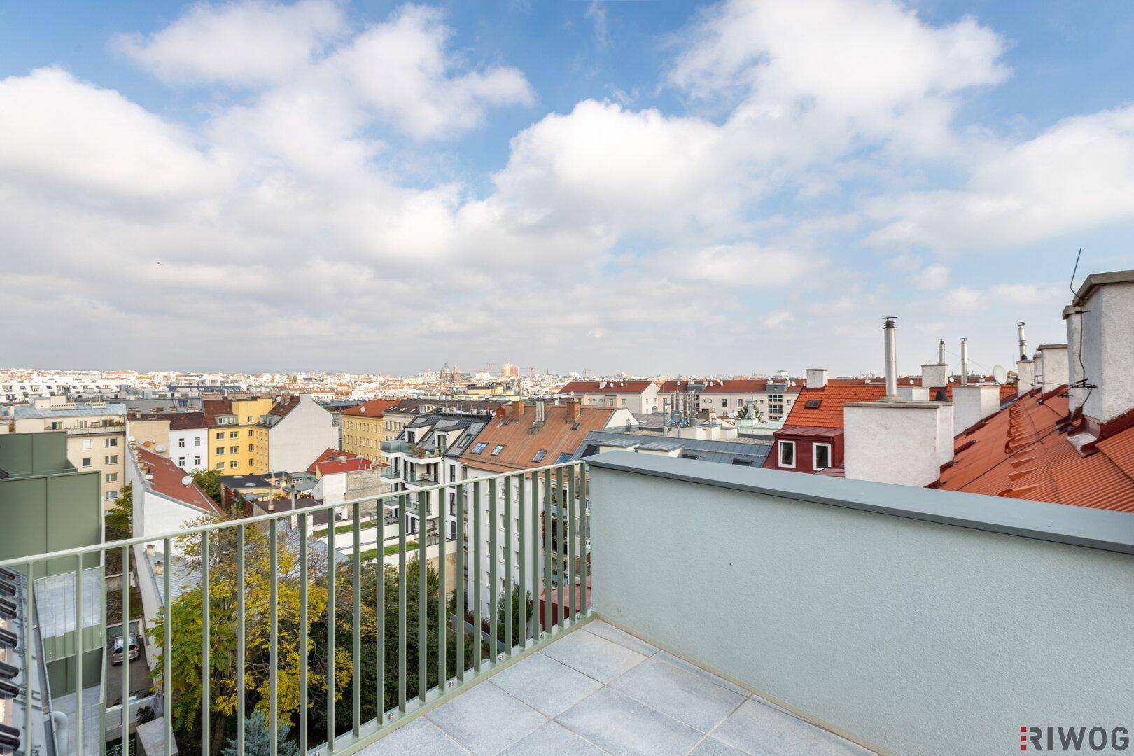 Sonniger Außenbereich auf der Dachterrasse mit Metallgeländer und weitem Blick über die Stadt.