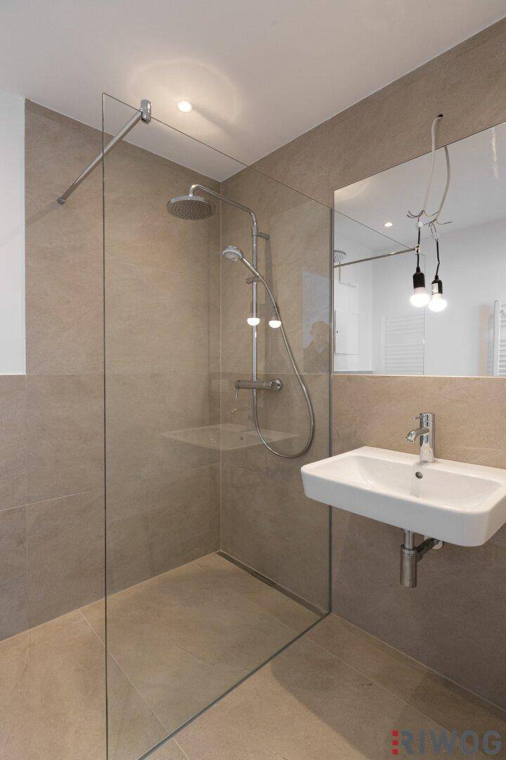 Elegantes Badezimmer mit begehbarer Dusche, modernem Waschbecken und großem Spiegel.