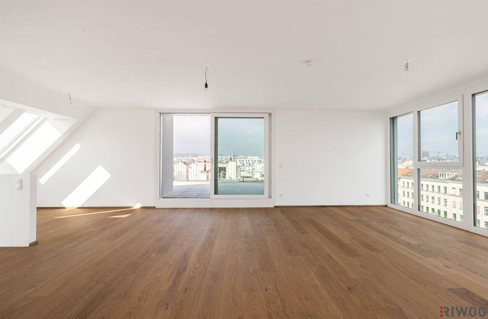 Geräumiger, heller Wohnbereich mit Holzboden und weitem Stadtblick durch große Fenster.