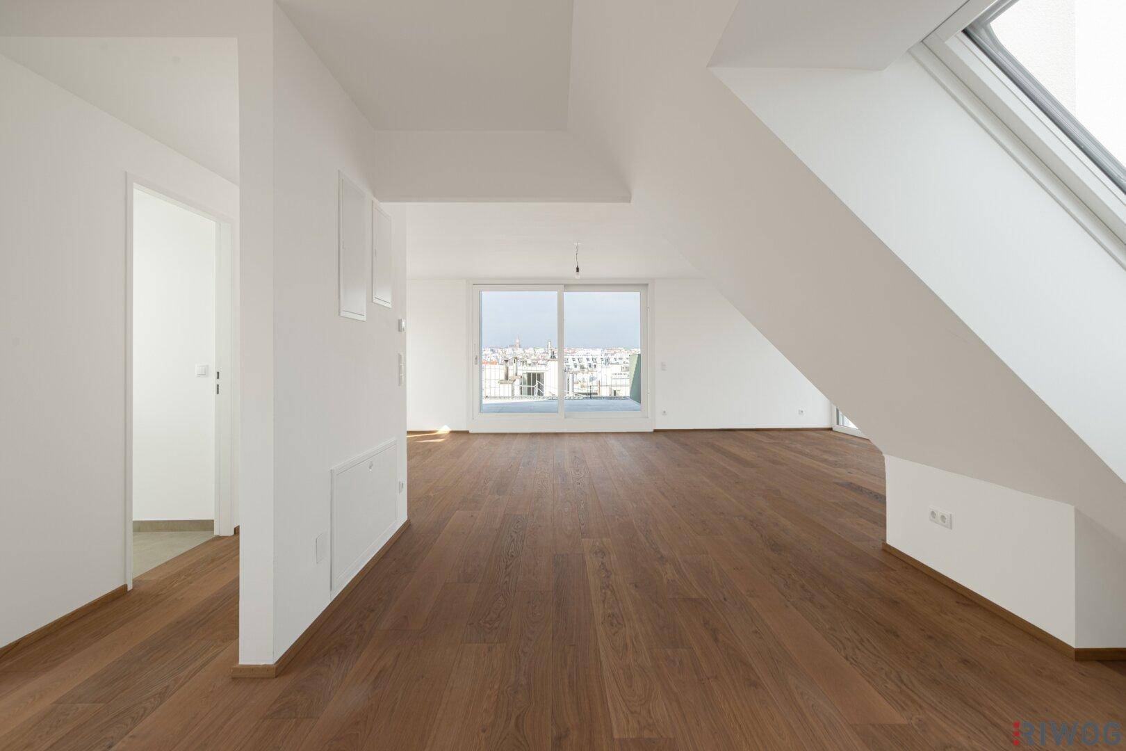 Heller Wohnraum im Dachgeschoss mit Holzboden und schrägen Wänden, bereit zur Einrichtung.