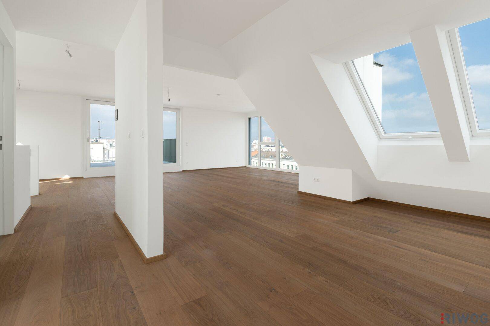 Geräumiger Dachgeschossraum mit Holzboden, großen Dachfenstern und viel Tageslicht.