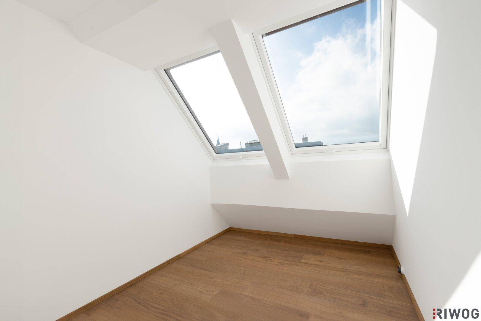 Helles Zimmer im Dachgeschoss mit Holzboden und großem Dachfenster, ideal als Schlaf- oder Arbeitszimmer.