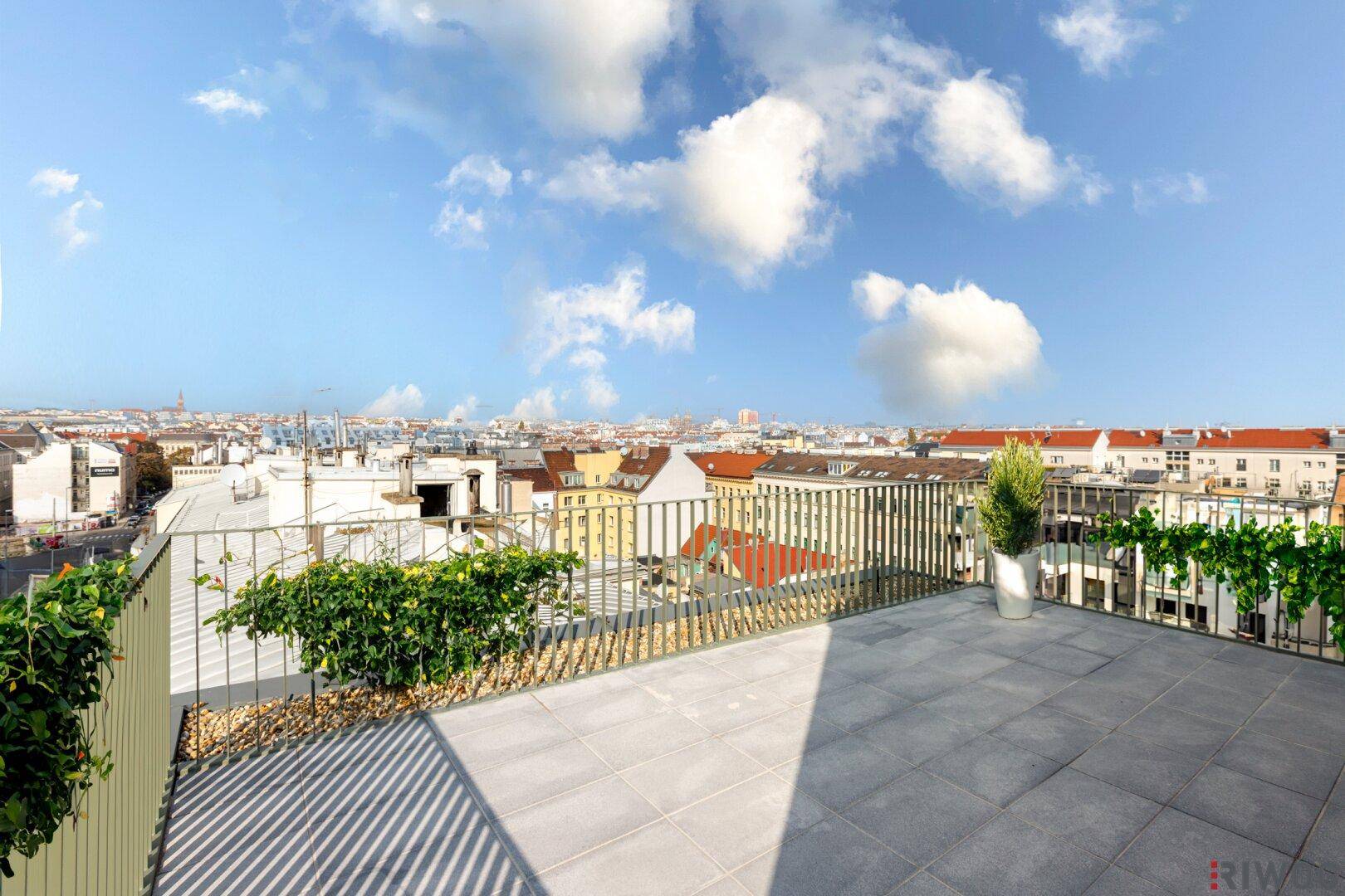 Geräumige Dachterrasse mit Stadtblick und Begrünung, ideal für Entspannung im Freien.
