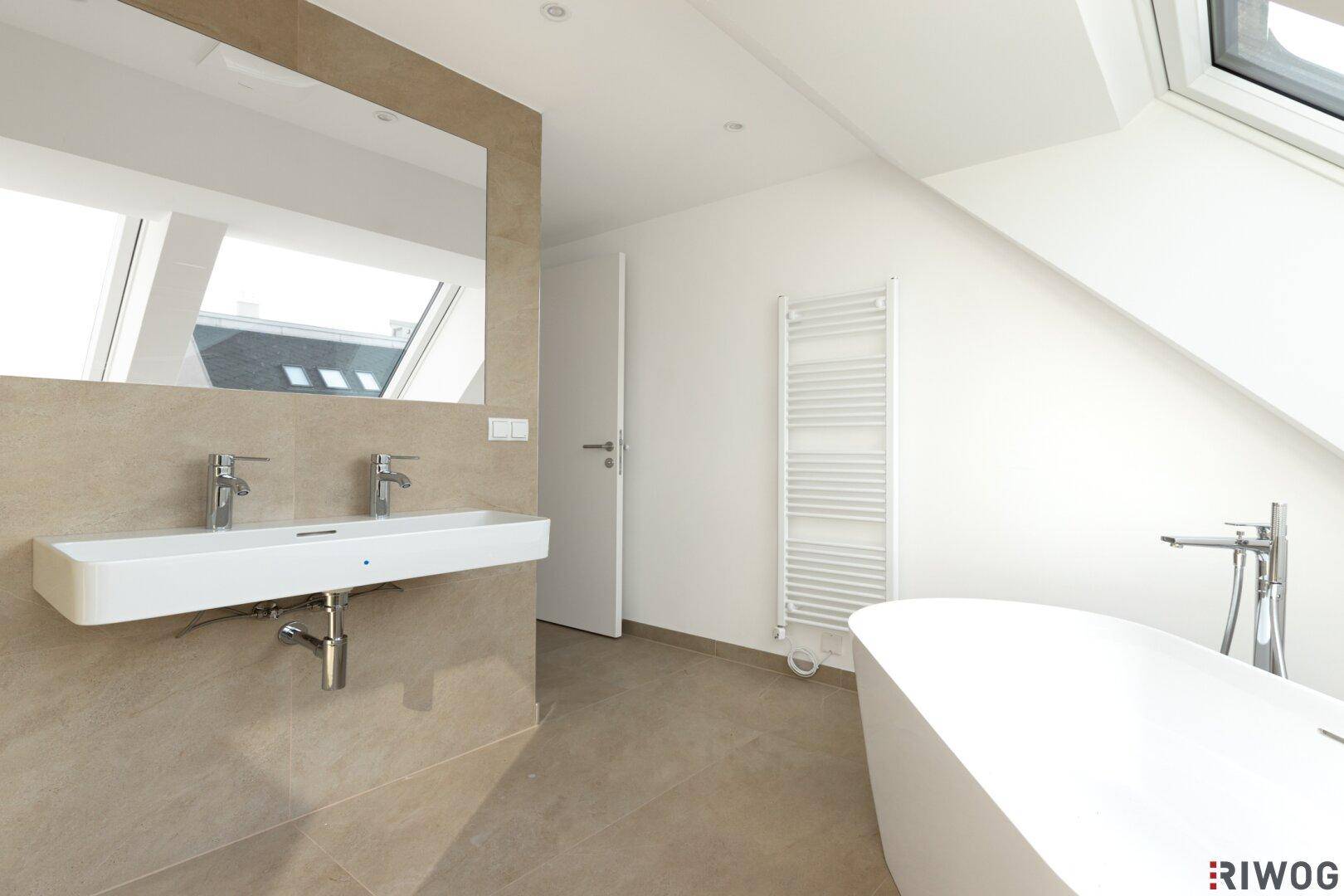 Elegantes Badezimmer mit Doppelwaschbecken, freistehender Badewanne und beheiztem Handtuchhalter.