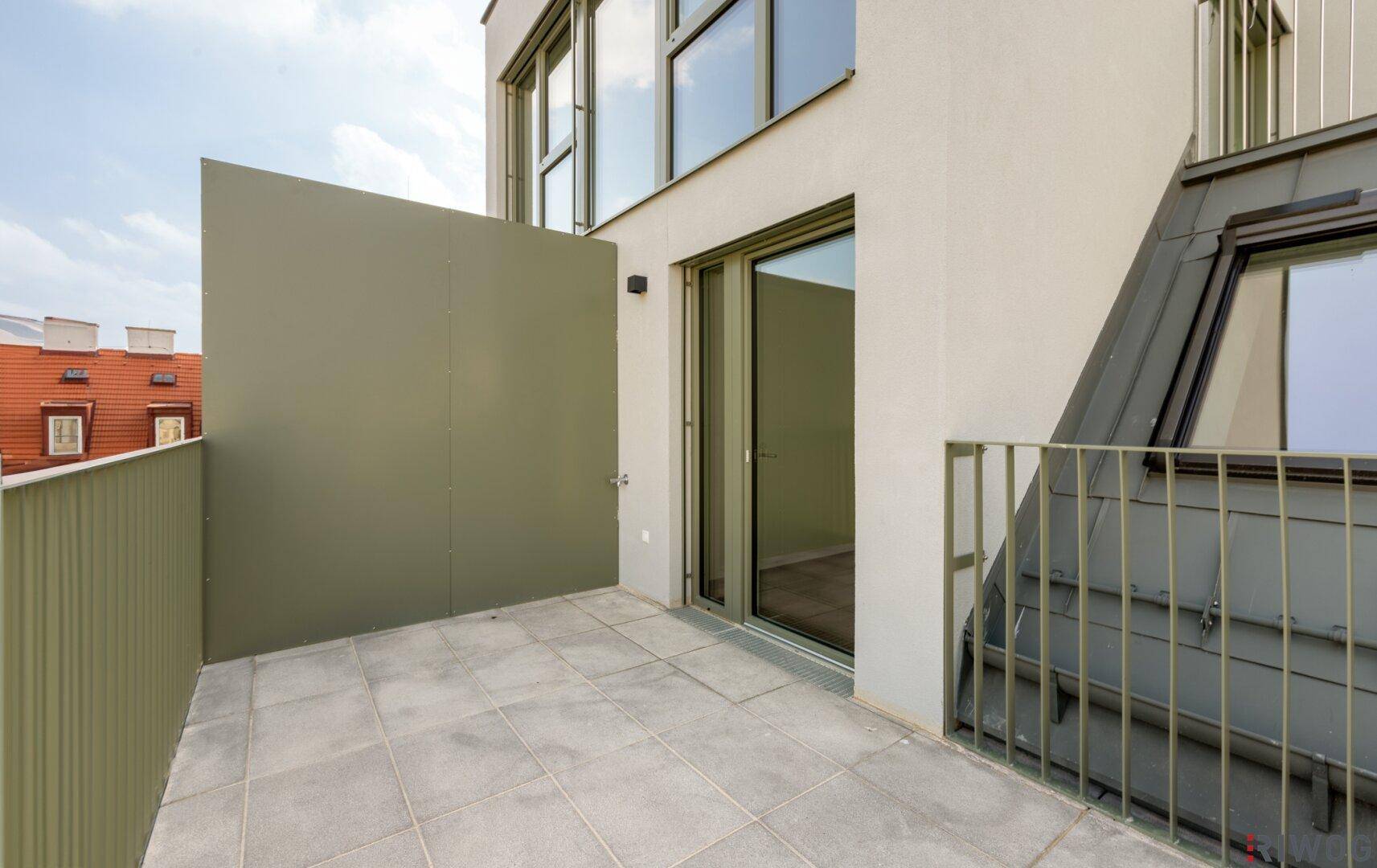 Moderner Balkon mit Fliesenboden und einer Sichtschutzwand für Privatsphäre.