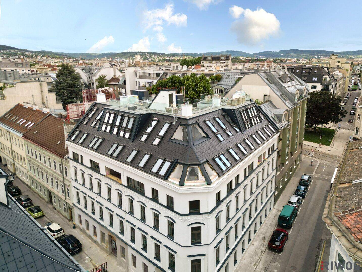 Weitläufiger Blick auf ein neuwertiges Gebäude mit markantem Dach und die städtische Umgebung.