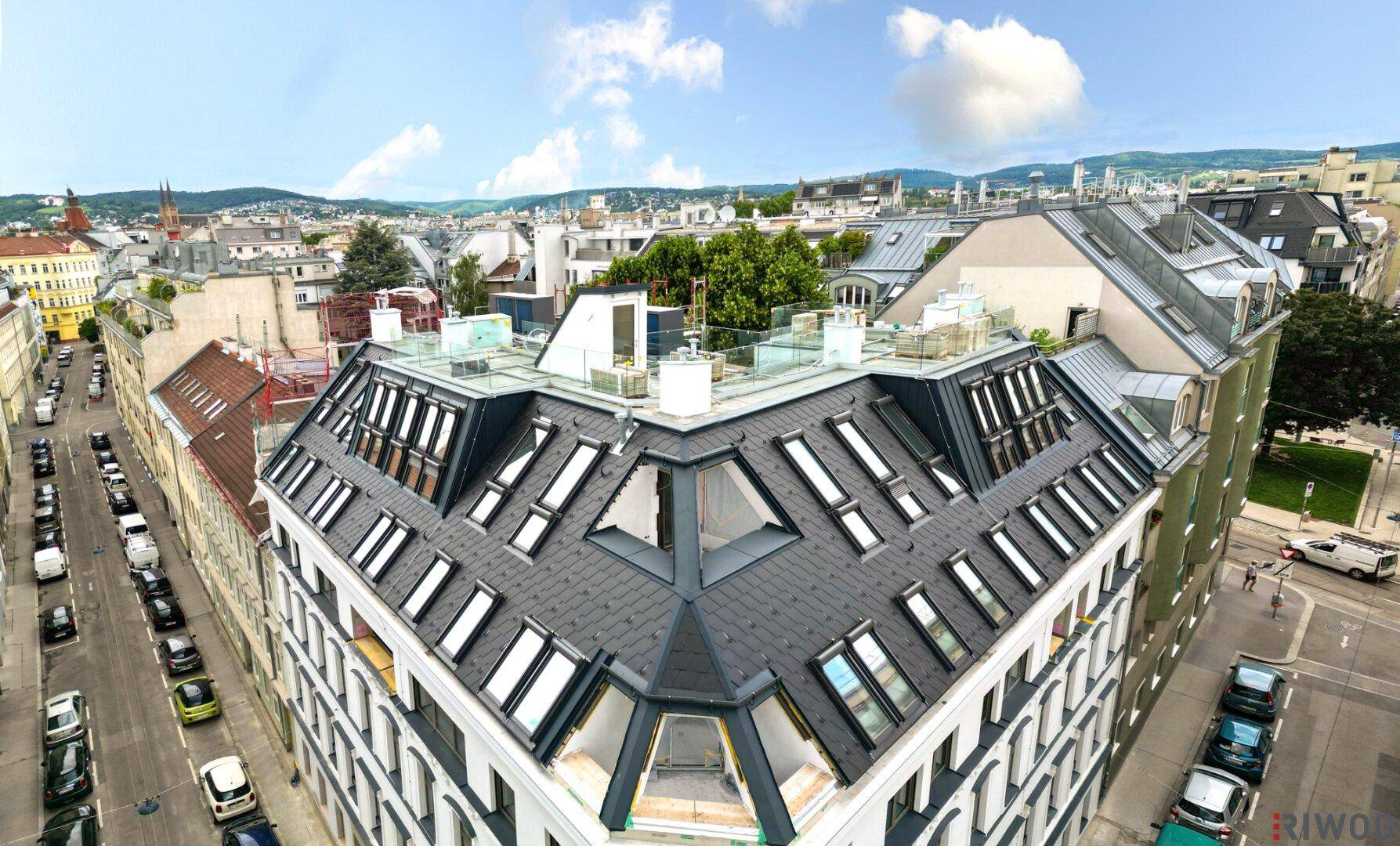 Panoramablick auf ein modernes Gebäude mit komplexer Dachkonstruktion und die umliegende Stadtlandschaft.
